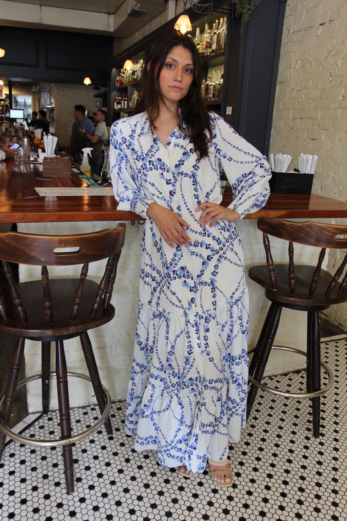 Model wearing MISA Los Angeles Evangeline maxi dress in intertwined white floral print styled for a coastal vacation dinner