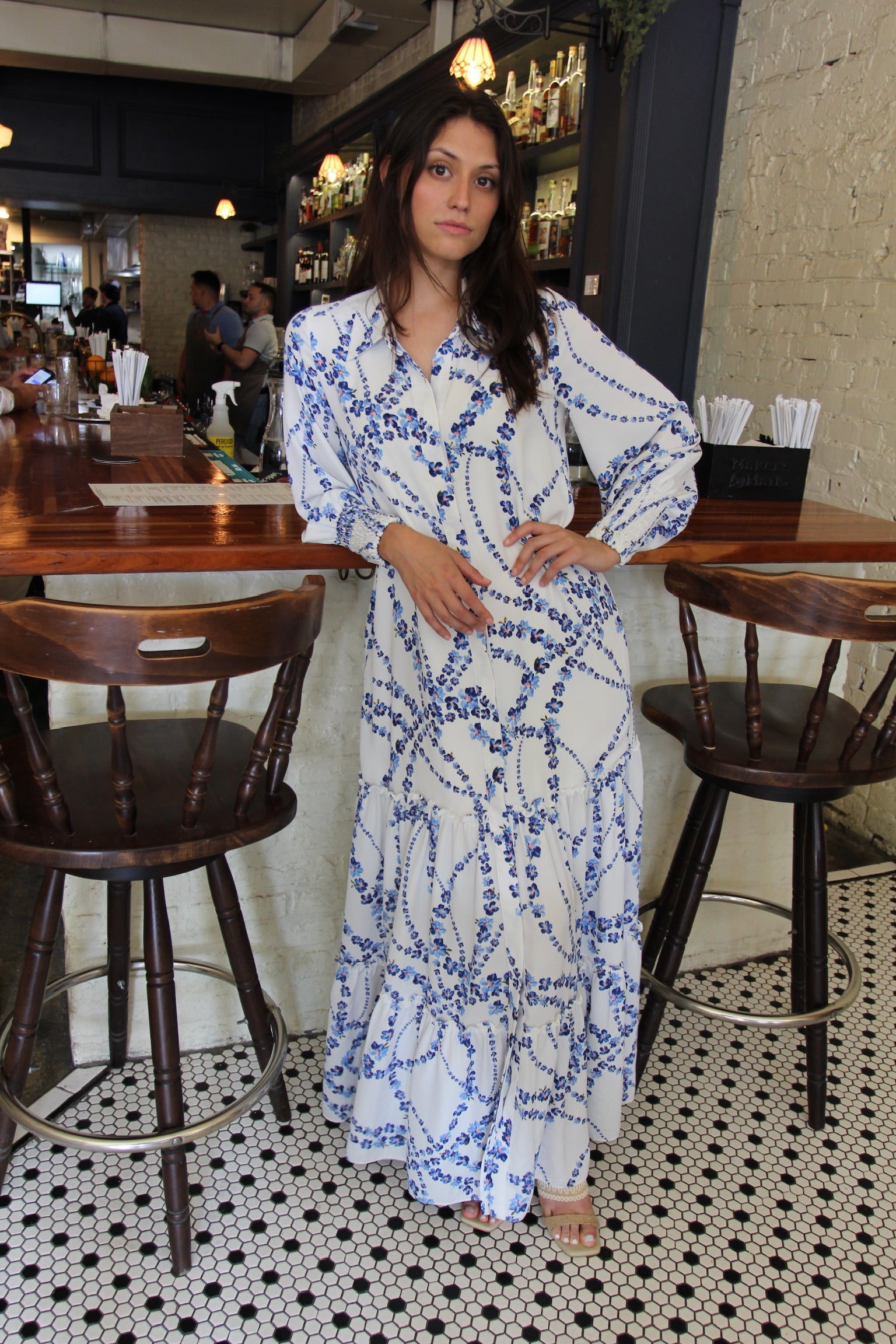 Model wearing MISA Los Angeles Evangeline maxi dress in intertwined white floral print styled for a coastal vacation dinner
