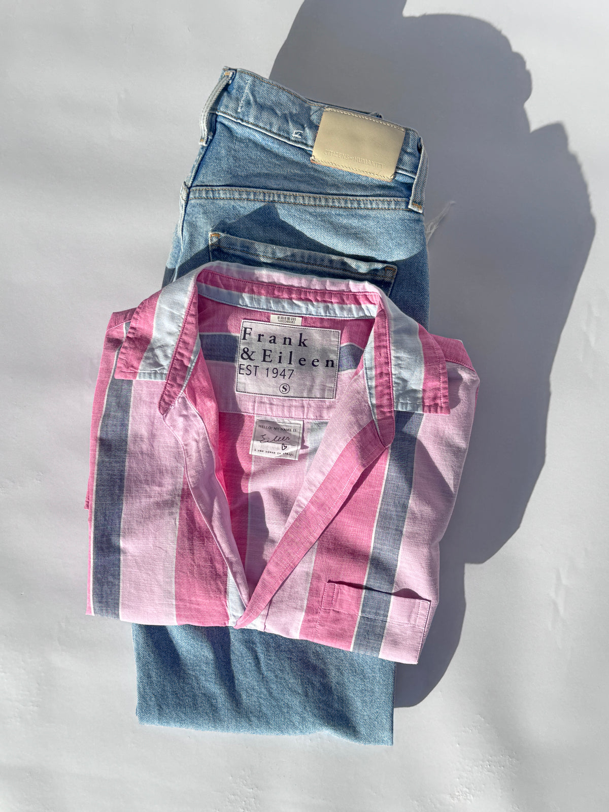 Pink and blue striped shirt and jeans on a light gray background